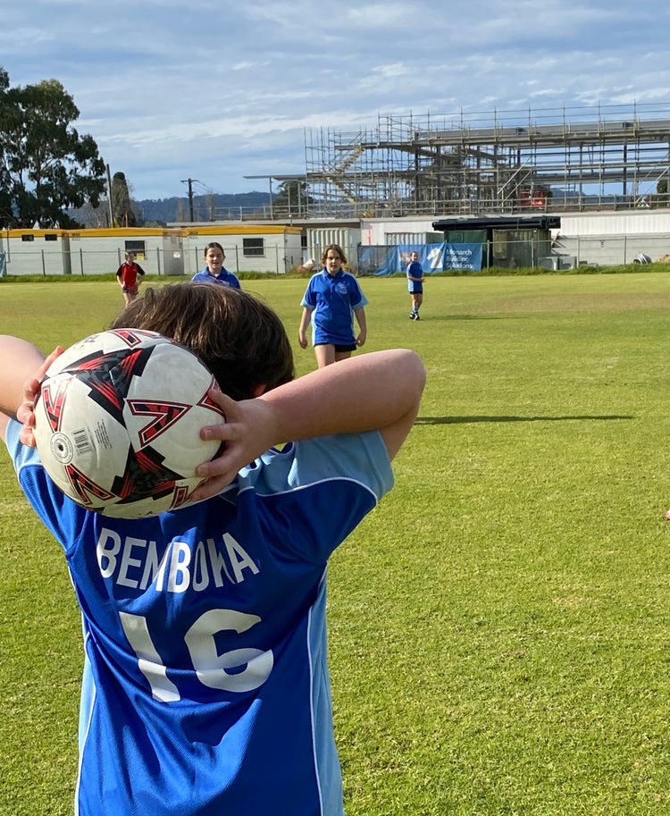 student throwing a soccer ball onto pitch