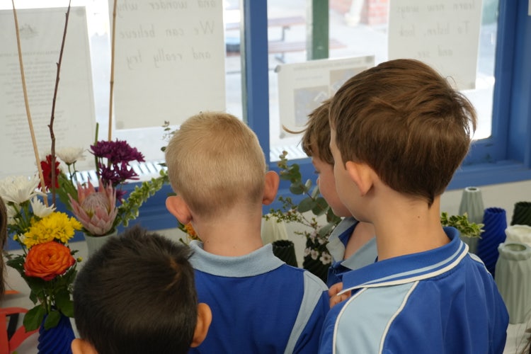 students with backs to camera looking at floral arrangements.
