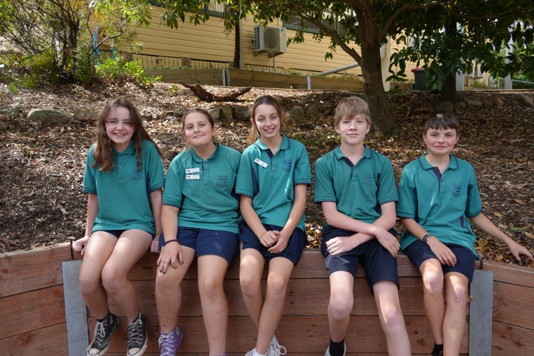 Year 6 school leaders sitting on the wall smiling at the camera