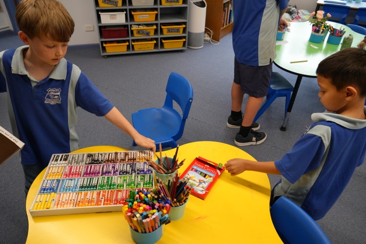 students at desk selecting pencils