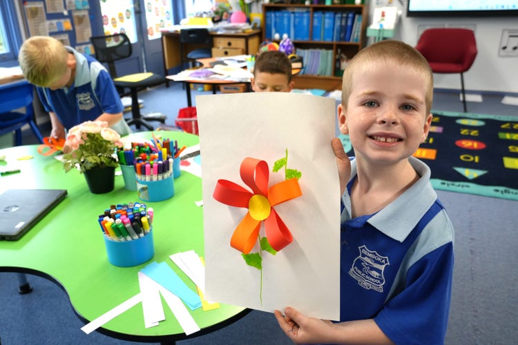 student holding up flower craft to the camera