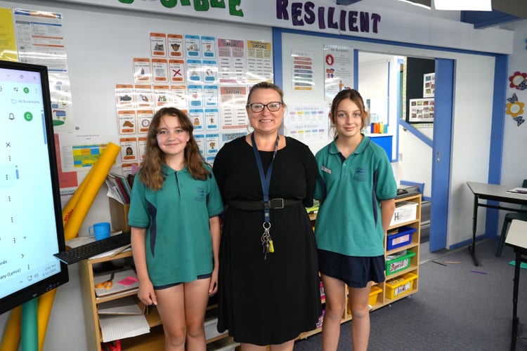 two student standing with principal smiling at camera