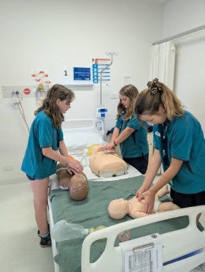 three students practicing CPR on dummies at UOW
