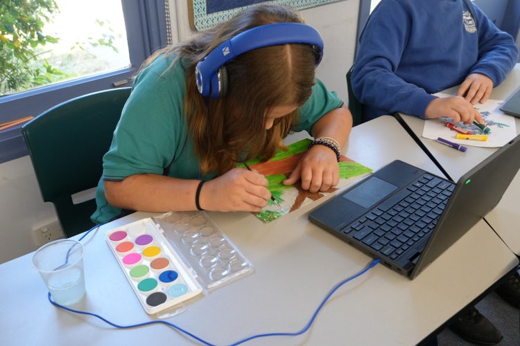 student watching a tutorial on painting with headphones on the laptop whilst painting