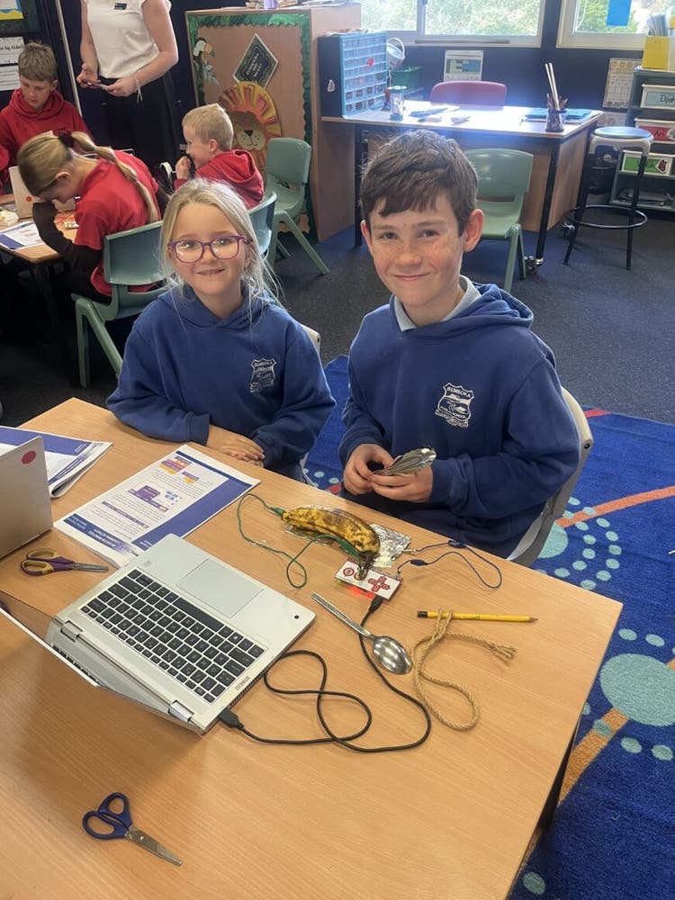 2 students sitting at desk with laptop