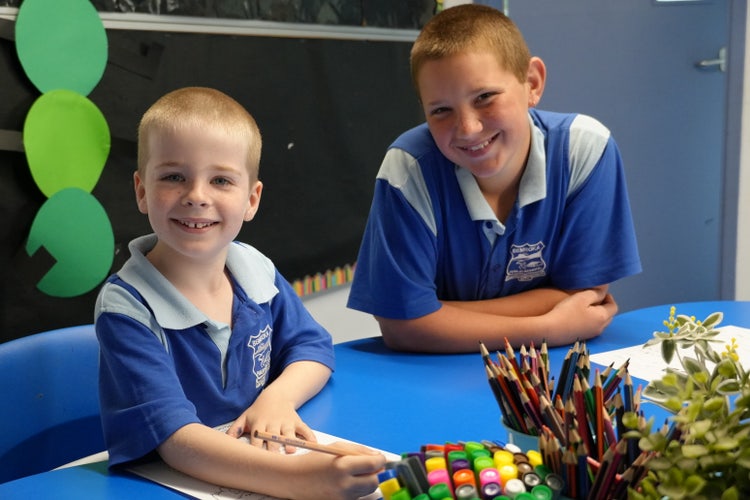 older student with younger student sitting at desk